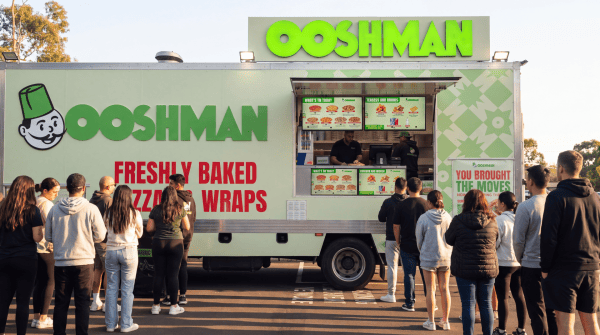 Customers queue at an OOSHMAN food truck serving freshly baked pizzas and wraps