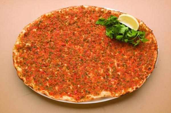 Lebanese meat flatbread served on a plate with lemon and fresh herbs