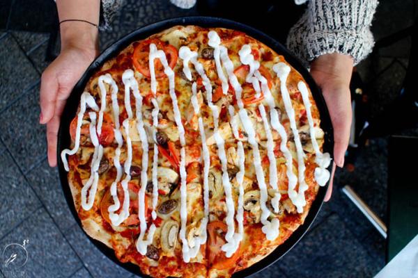 Overhead view of a loaded pizza topped with chicken, herbs and creamy sauce