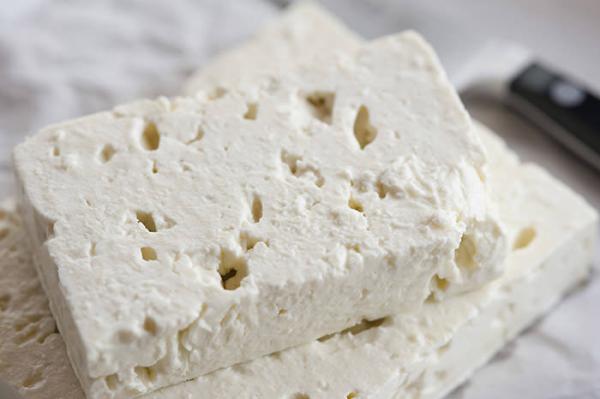 Close-up of crumbly white feta cheese blocks on a wooden board
