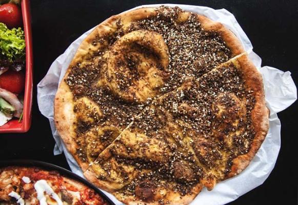 Freshly baked zaatar manoosh topped with a generous blend of herbs and sesame seeds