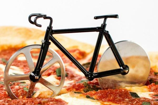 Miniature black bicycle pizza cutter resting on a pepperoni pizza