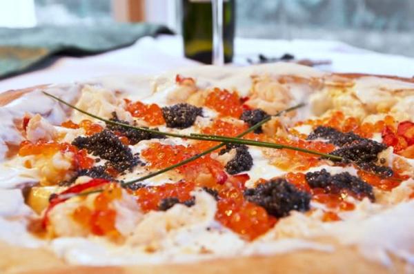 Close-up of a Lebanese-style pizza with creamy cheese, roasted red peppers, black olives and fresh chives