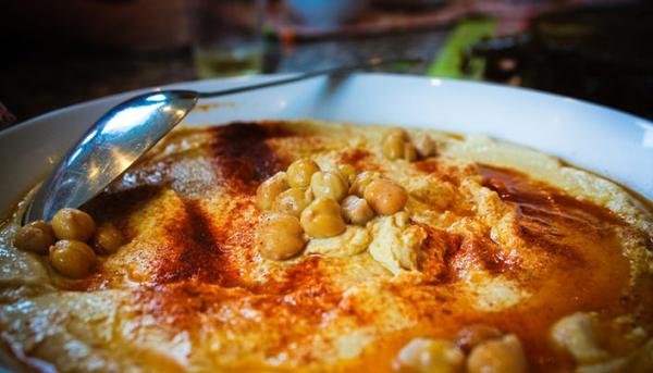 Creamy hommus topped with chickpeas, olive oil and paprika, served with a spoon