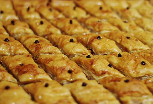 Close-up of golden Lebanese baklava fingers topped with dark spice seeds