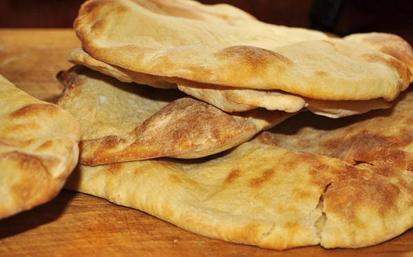 Stack of golden, freshly baked Lebanese flatbreads on a wooden board