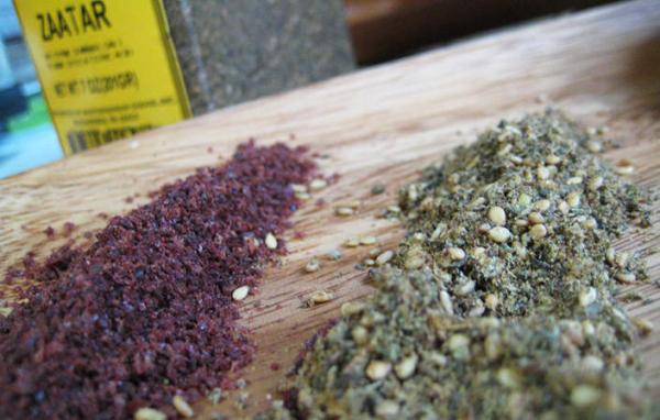 Two piles of zaatar spice blend on a wooden board beside a zaatar packet