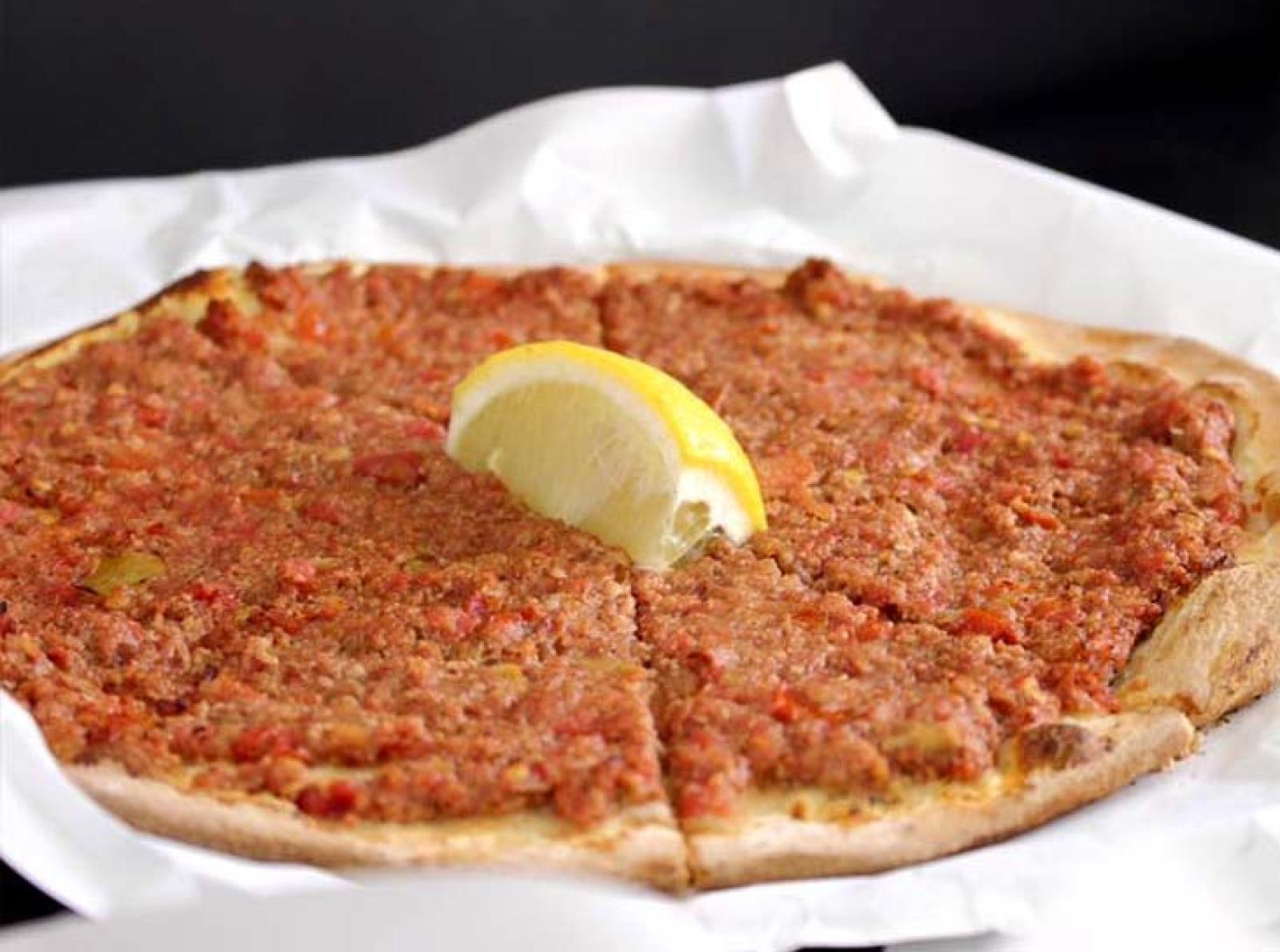 Lebanese lahembajin flatbread topped with seasoned minced meat and lemon wedges