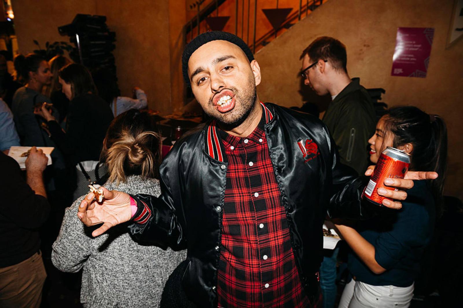 Man holding a canned drink and posing at a busy indoor party