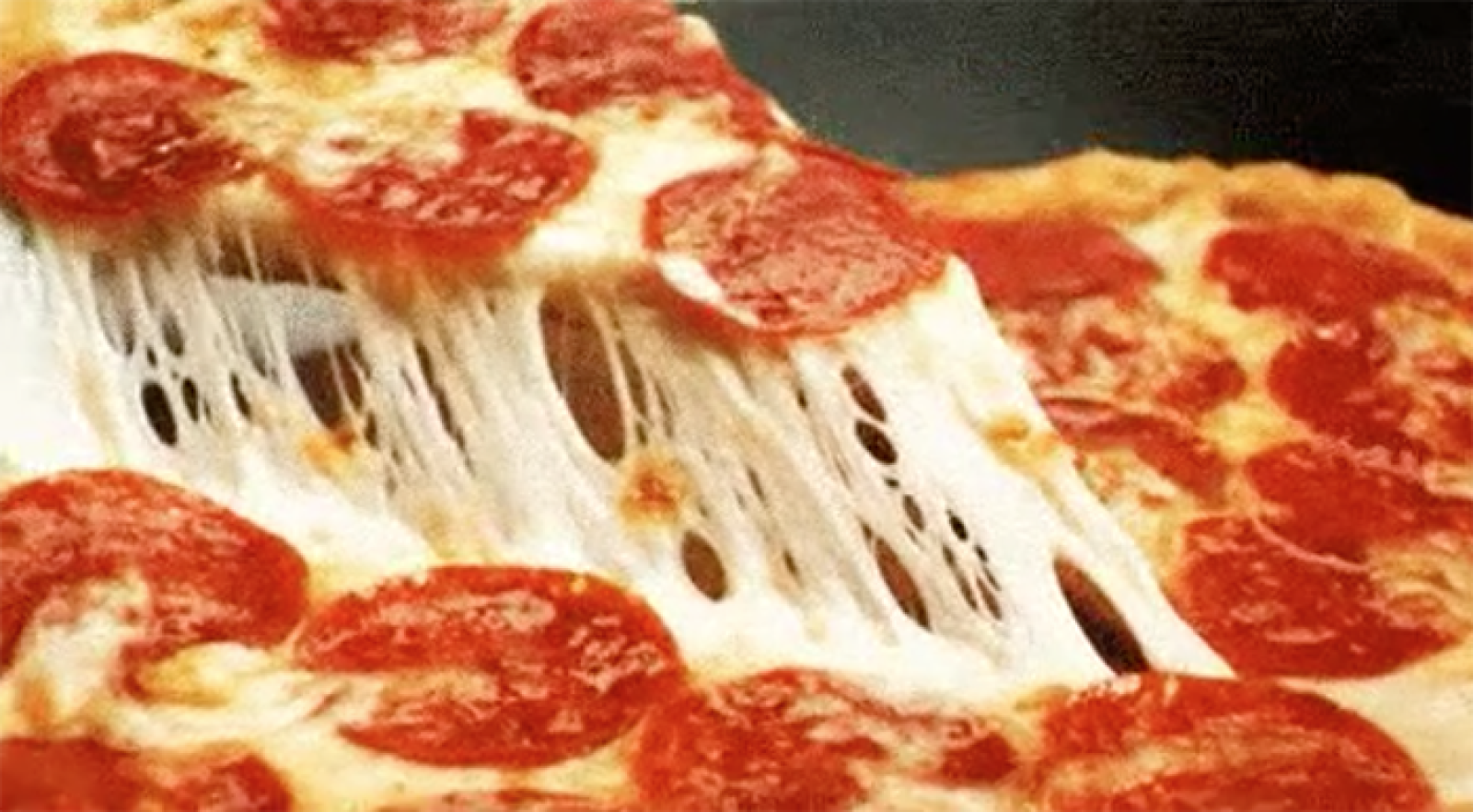 Slice of pepperoni pizza lifted from a cheesy pizza with long strands of melted mozzarella
