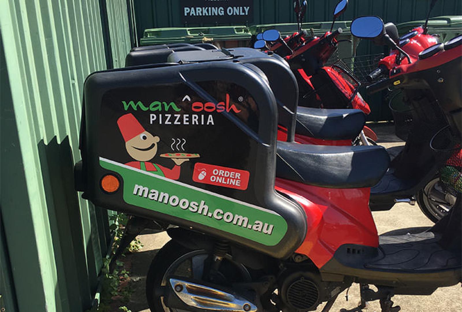 Red Manoosh Pizzeria delivery scooter parked beside other motorbikes