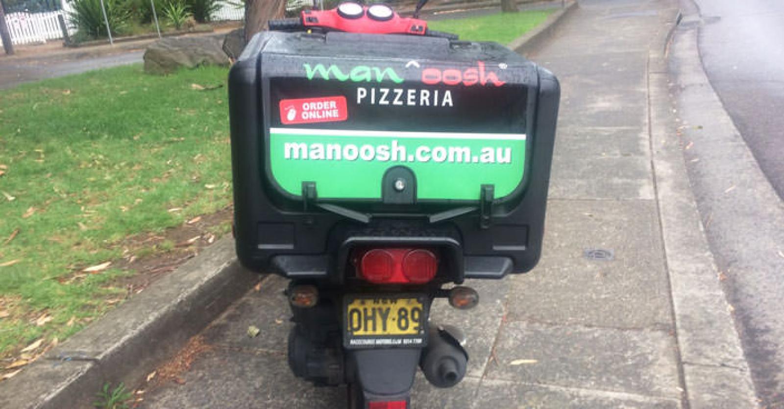 Branded Manoosh Pizzeria delivery scooter parked beside a suburban street