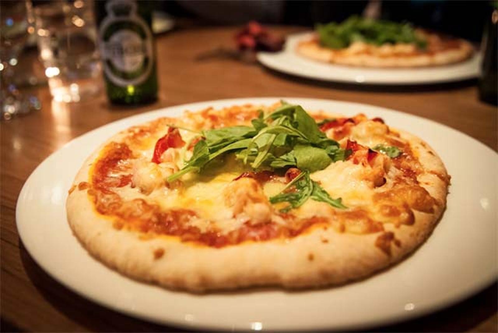 Freshly baked cheese pizza with tomato sauce and basil served on a white plate