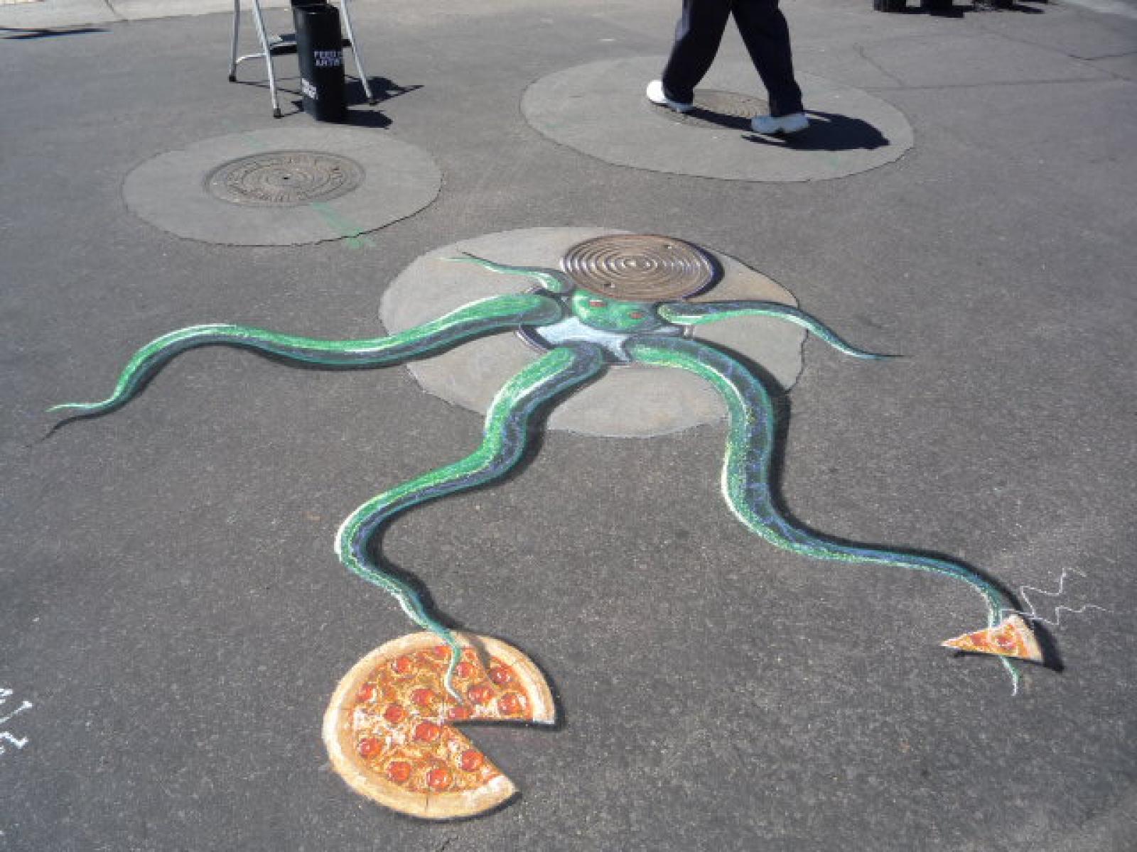 Pavement artwork of a green octopus reaching towards pizza slices as pedestrians walk past