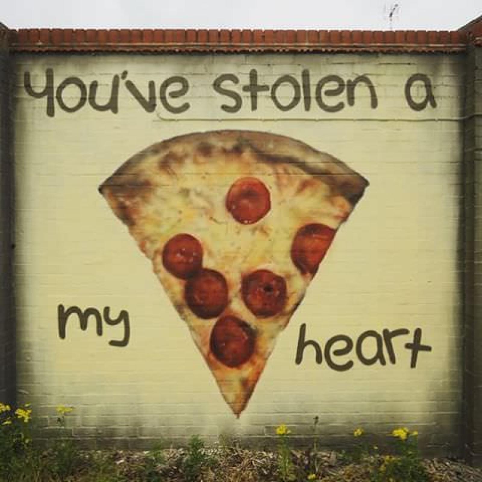 Street mural of a pepperoni pizza slice beneath the words “You’ve stolen a my heart”