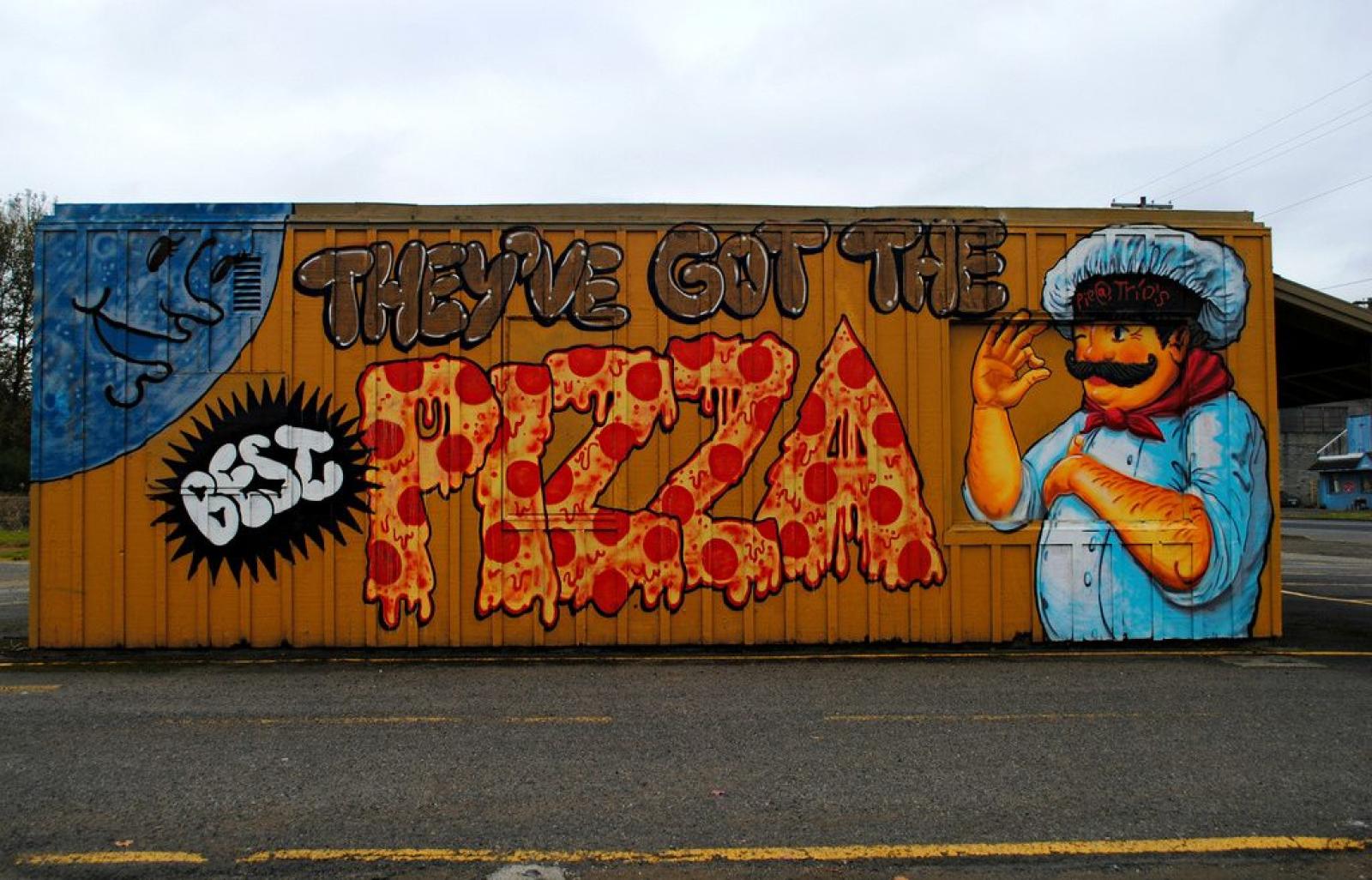 Colourful street-art mural with a pizza slice and illustrated character on an orange shopfront wall