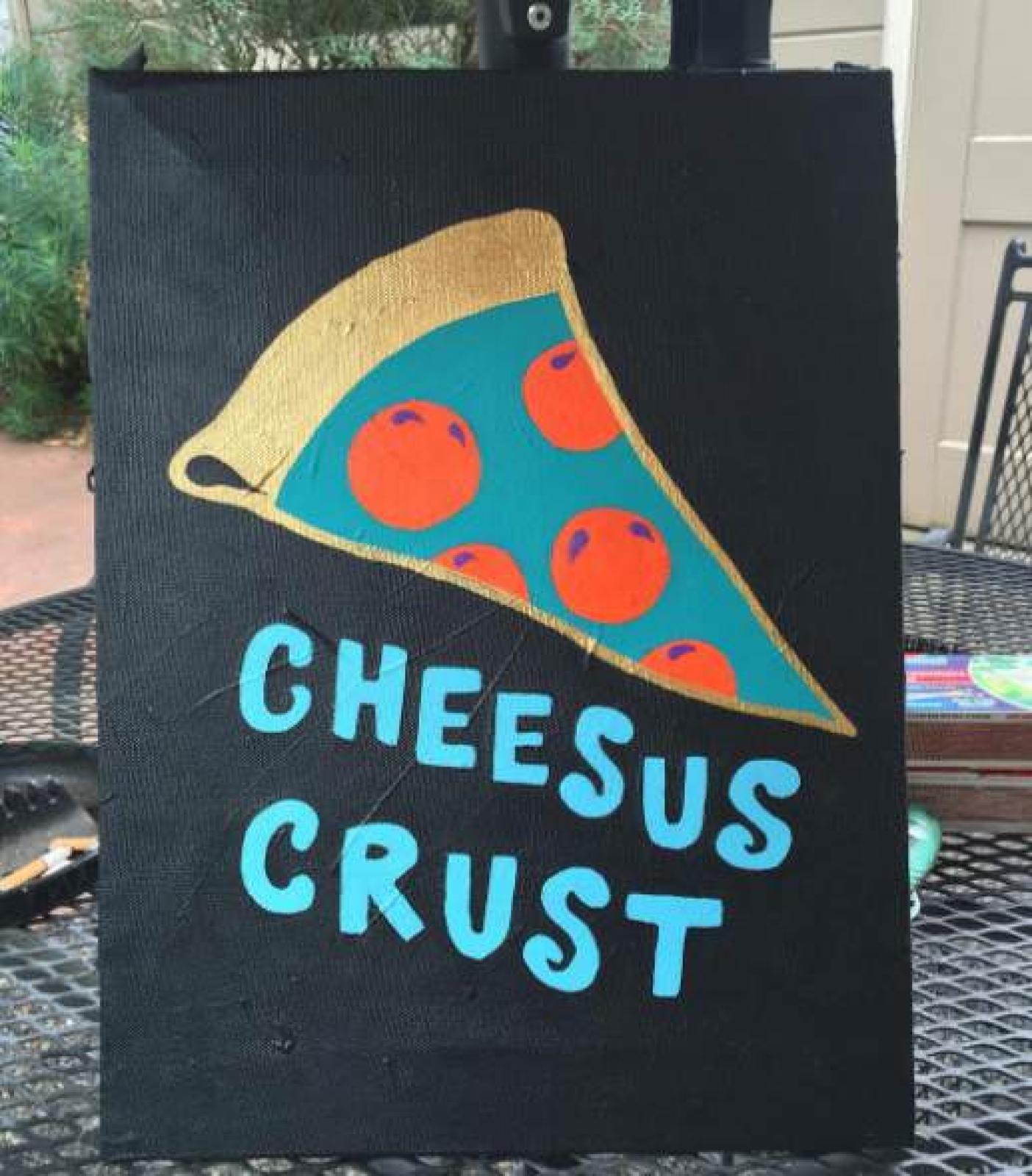 Black sign with a colourful pepperoni pizza slice and the words “Cheesus Crust”