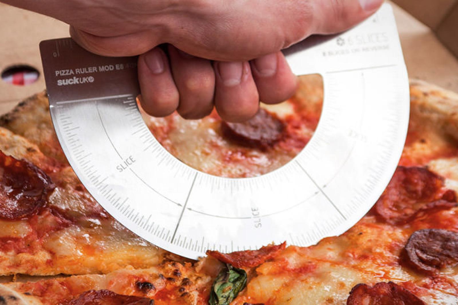 Hand holding a circular pizza portion guide over a pepperoni pizza