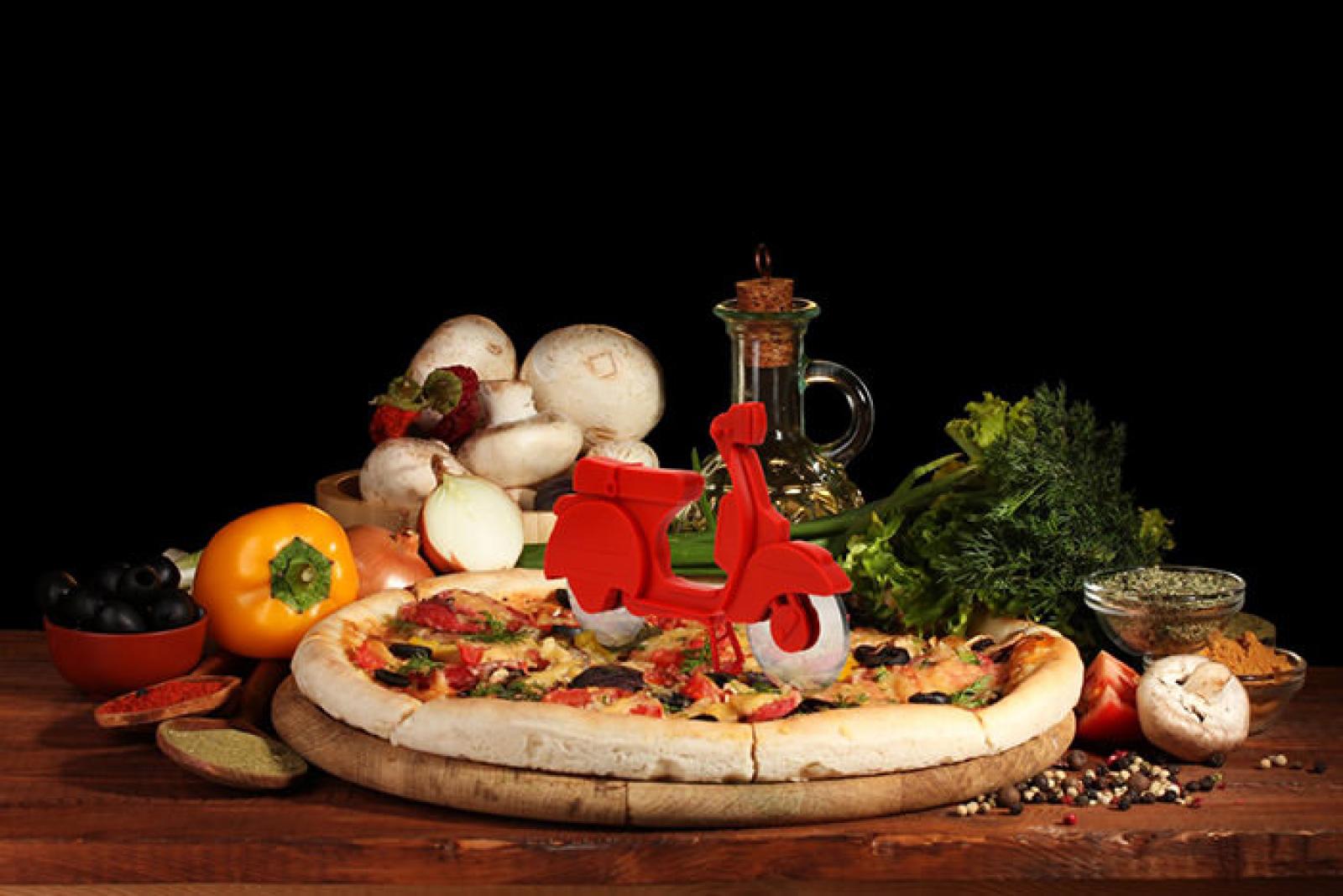 Freshly baked vegetable pizza with mushrooms, herbs and a red scooter on a wooden table