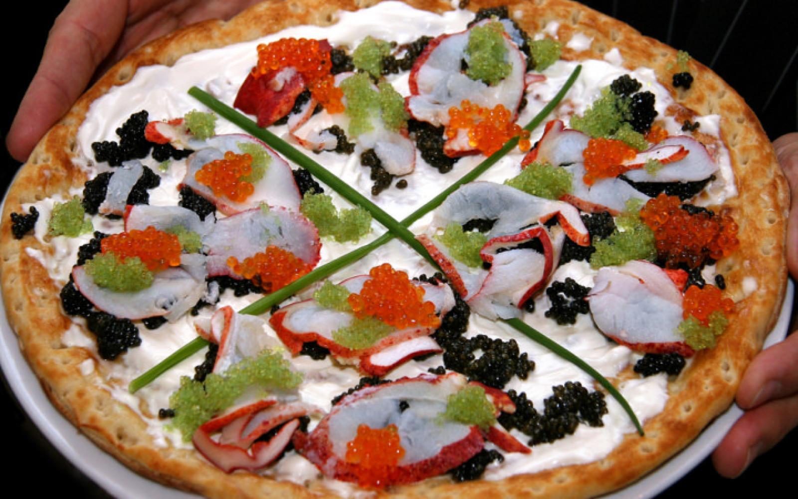 Gourmet seafood pizza topped with cheese, tomato, herbs and black roe
