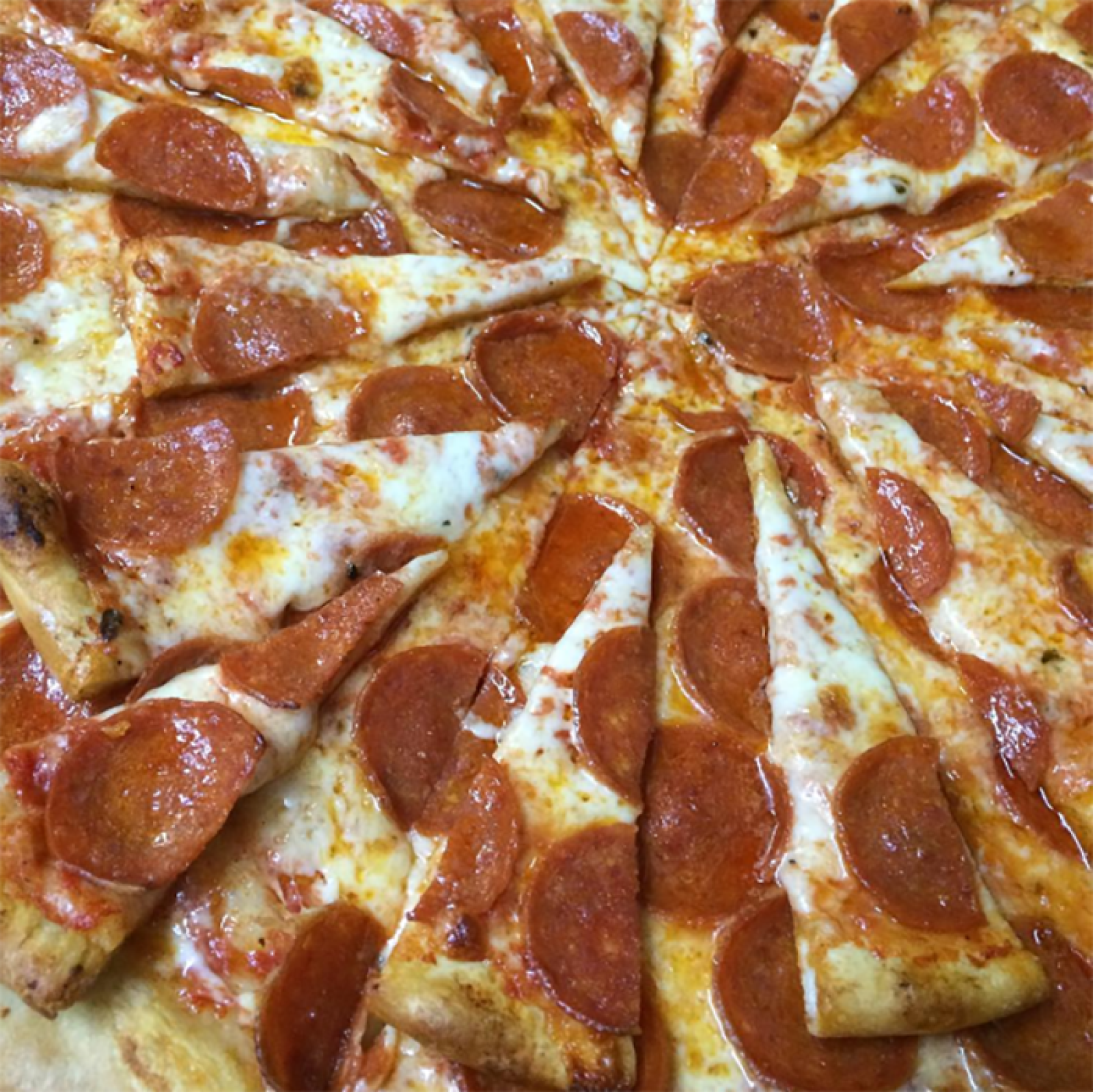 Close-up of a sliced pepperoni pizza topped with melted cheese and crisp pepperoni