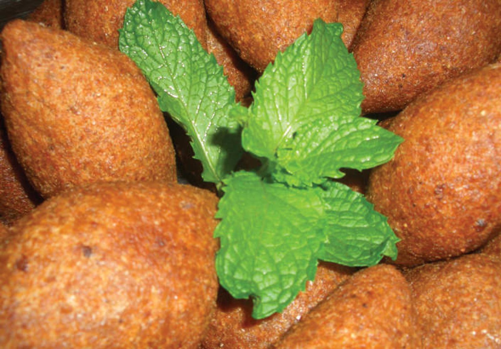 Golden fried lamb kebbeh arranged around fresh mint leaves