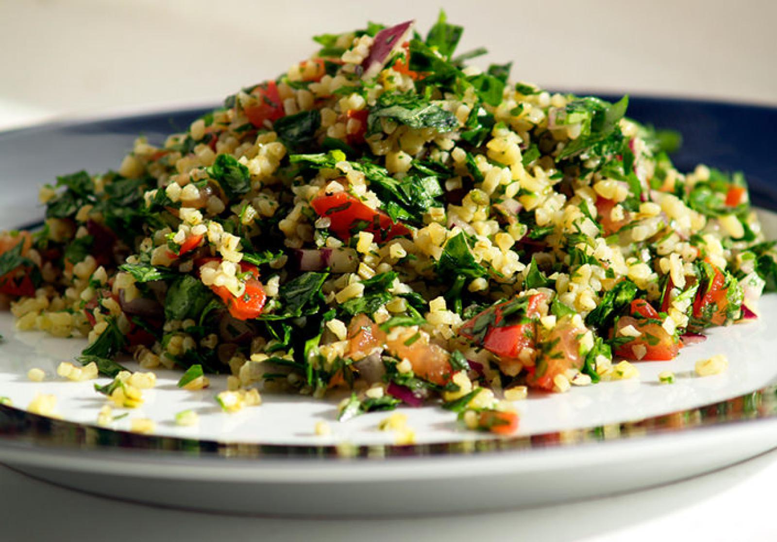 Fresh tabouli salad with bulgur, parsley, tomato and herbs on a white plate