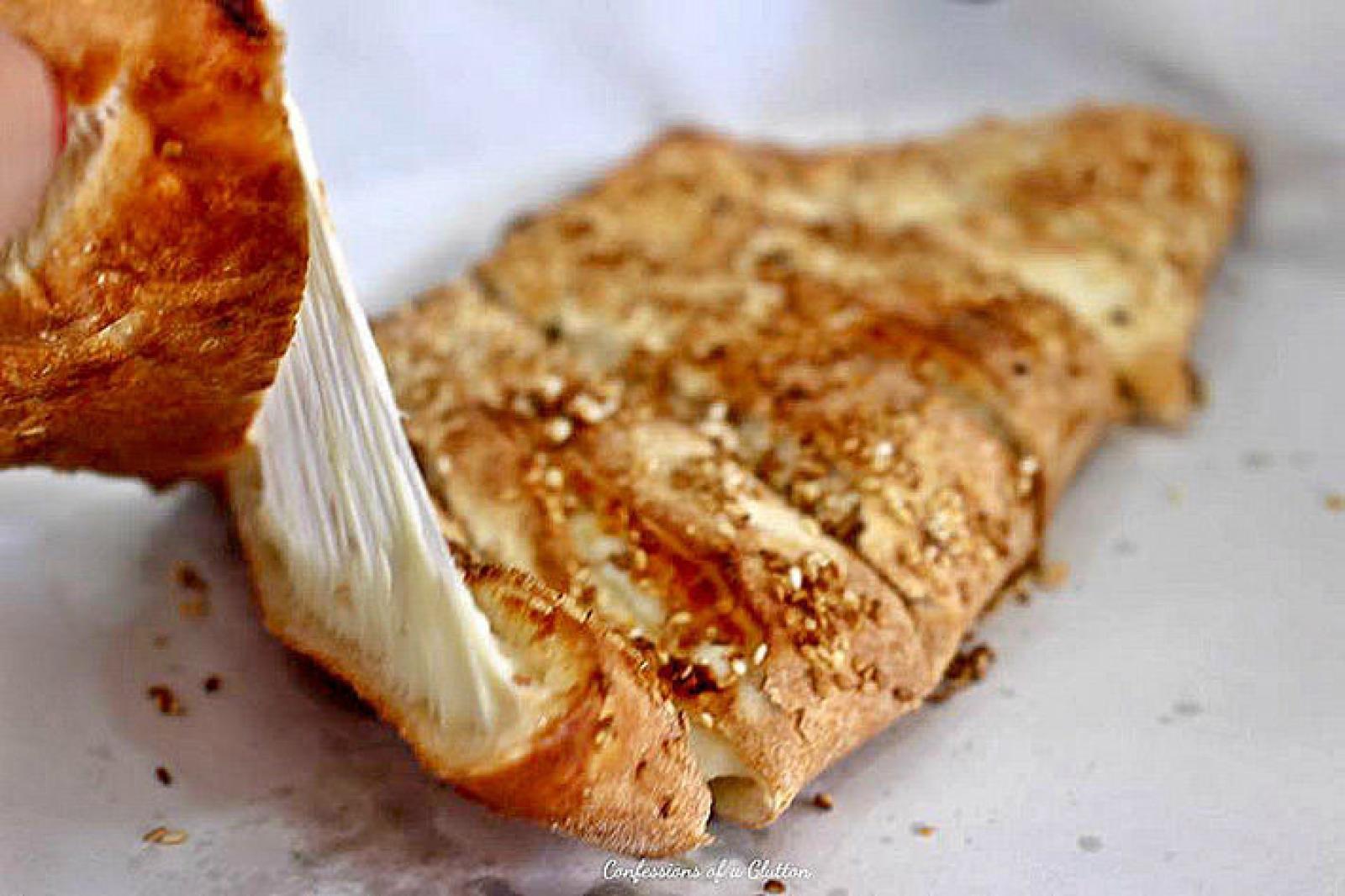Pastry brush spreading garlic butter over a grilled folded Lebanese flatbread