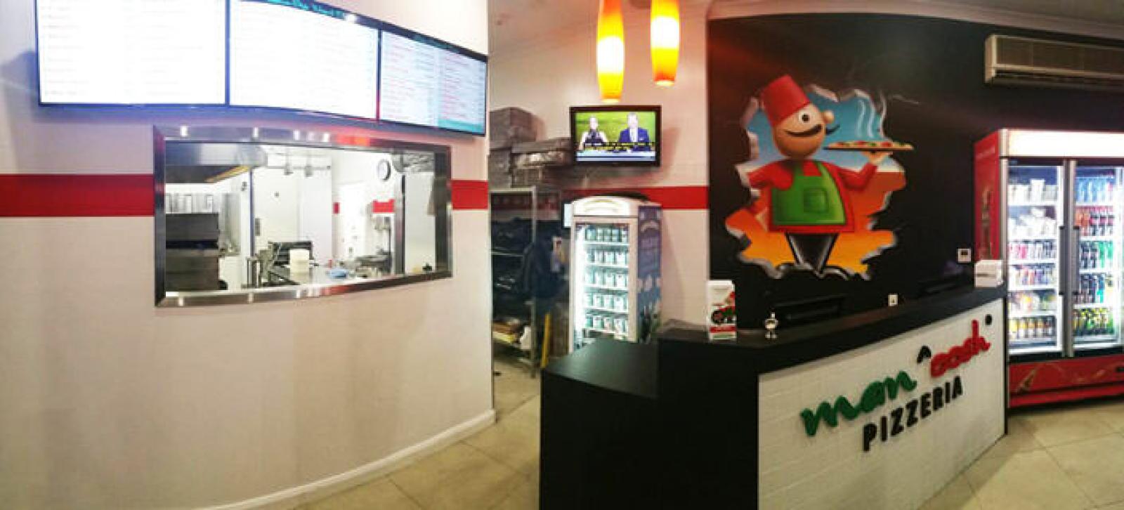 Interior of a Manoosh Pizzeria with service counter, mascot mural and chilled drinks
