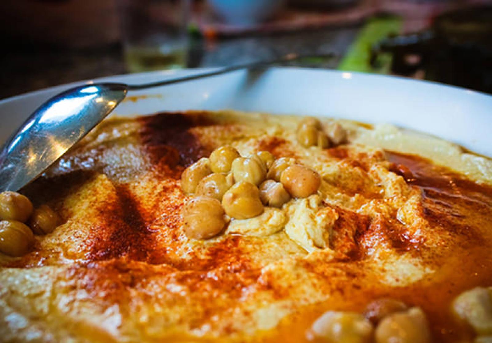 Creamy hommus topped with chickpeas, olive oil and paprika in a white bowl