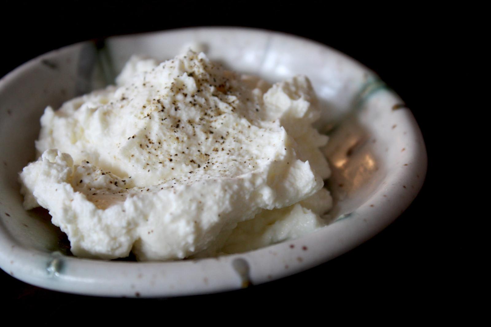 Bowl of creamy labne dip topped with olive oil and cracked black pepper