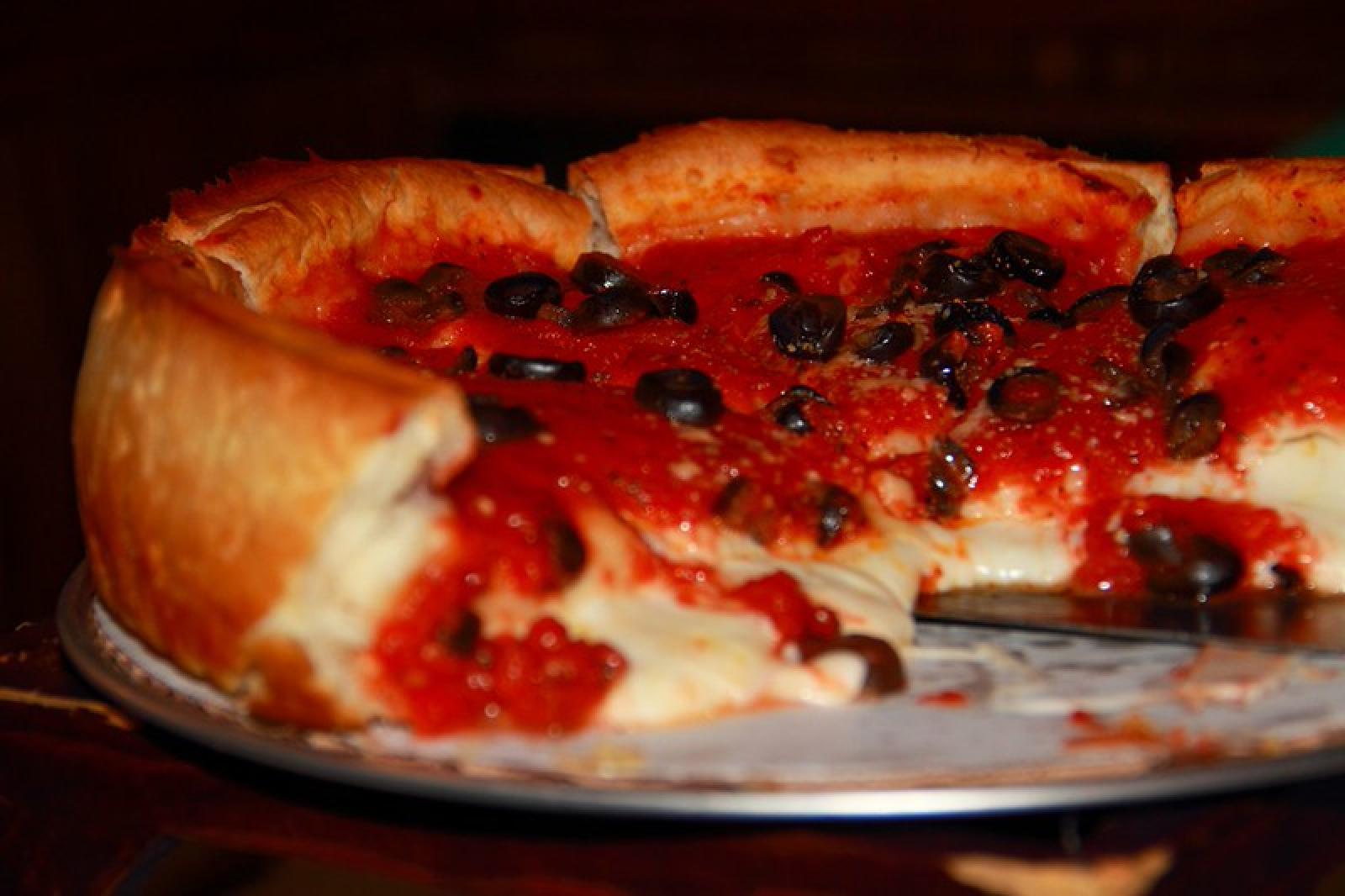 Close-up of a thick-crust pizza with tomato sauce, melted cheese and black olives