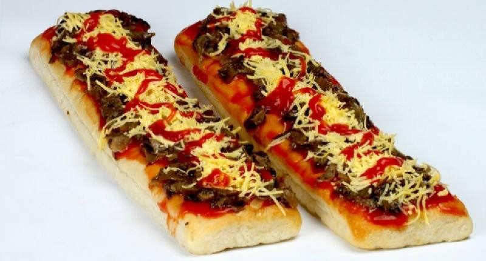 Two Lebanese meat and cheese pizza boats topped with tomato sauce and herbs