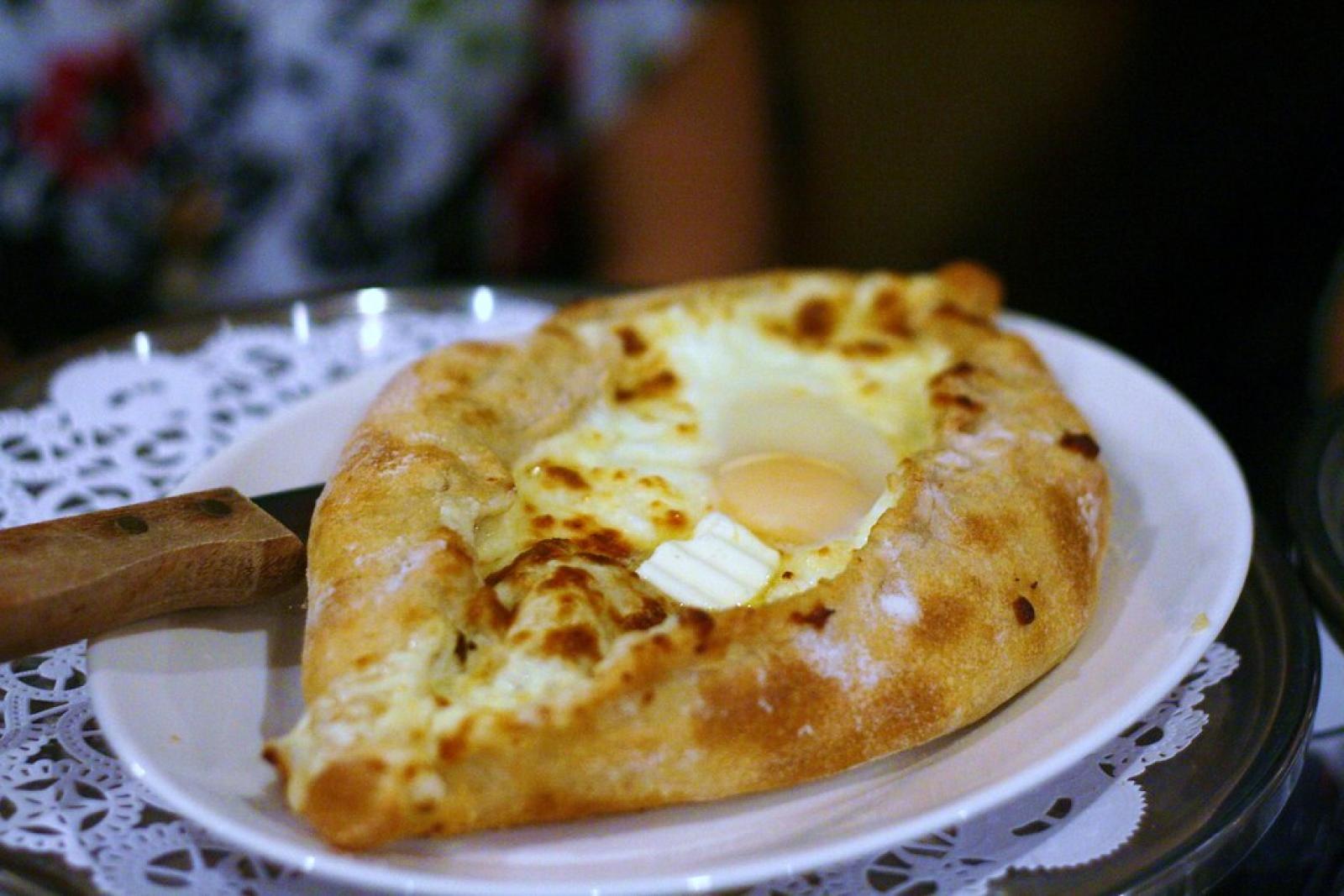 Golden cheese-filled flatbread topped with a baked egg on a white plate