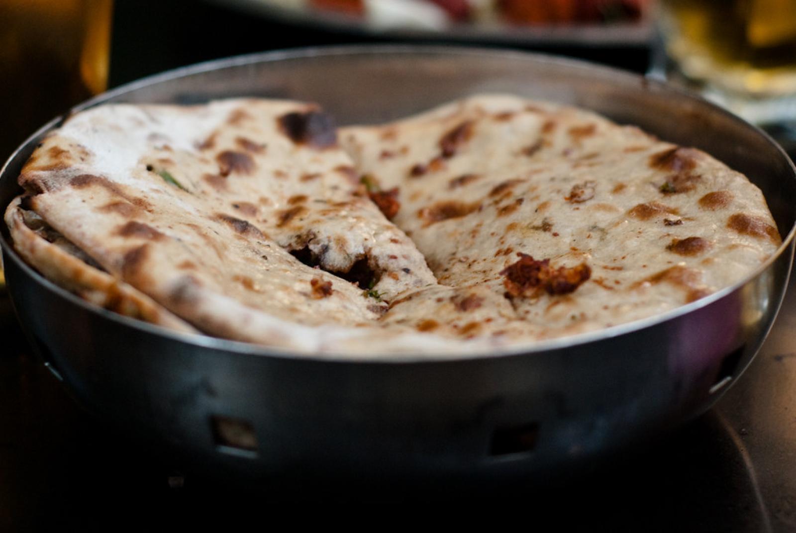 Freshly baked Lebanese flatbreads folded in a metal serving pan