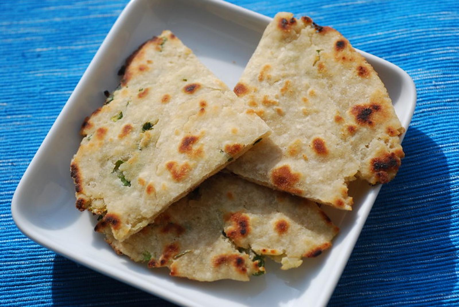 Three folded Lebanese cheese pastries with golden grilled spots on a white plate