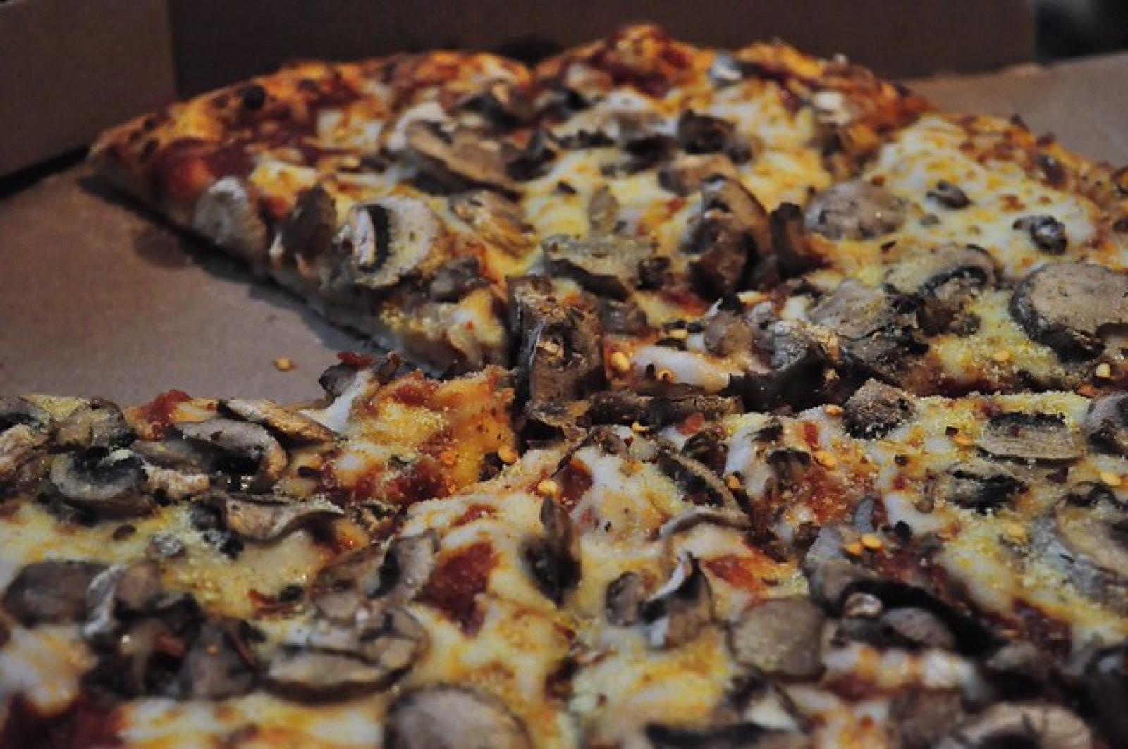 Close-up of sliced pizza topped with mushrooms, black olives and melted cheese