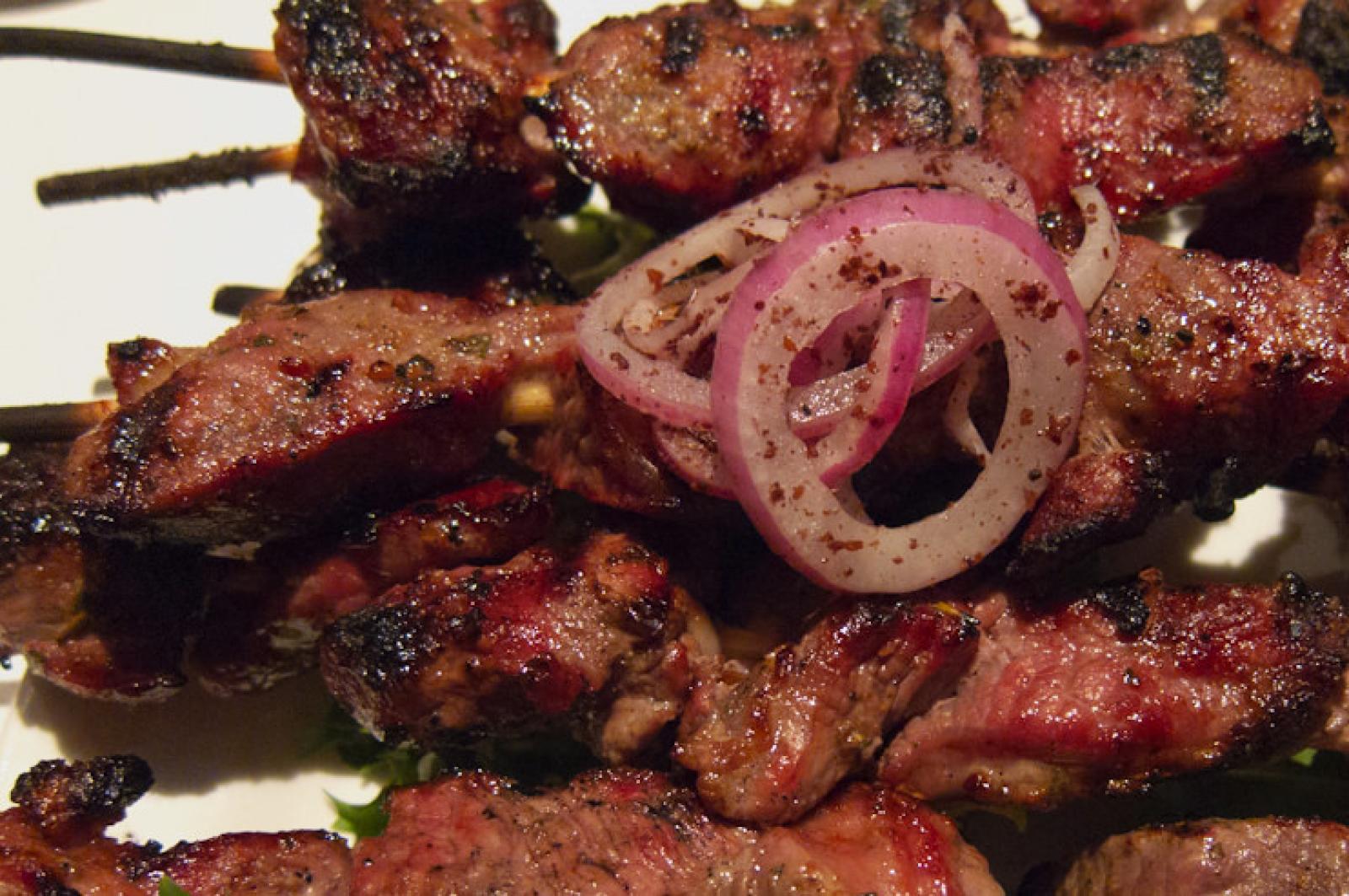 Grilled minced meat skewers with sliced red onion garnish