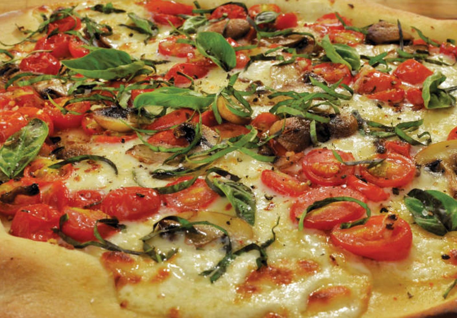 Vegetarian pizza topped with cherry tomatoes, mushrooms, spinach and melted cheese