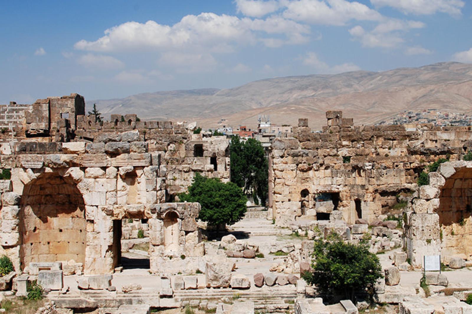 Ancient stone ruins at Baalbek, Lebanon, beneath a blue sky and mountain backdrop