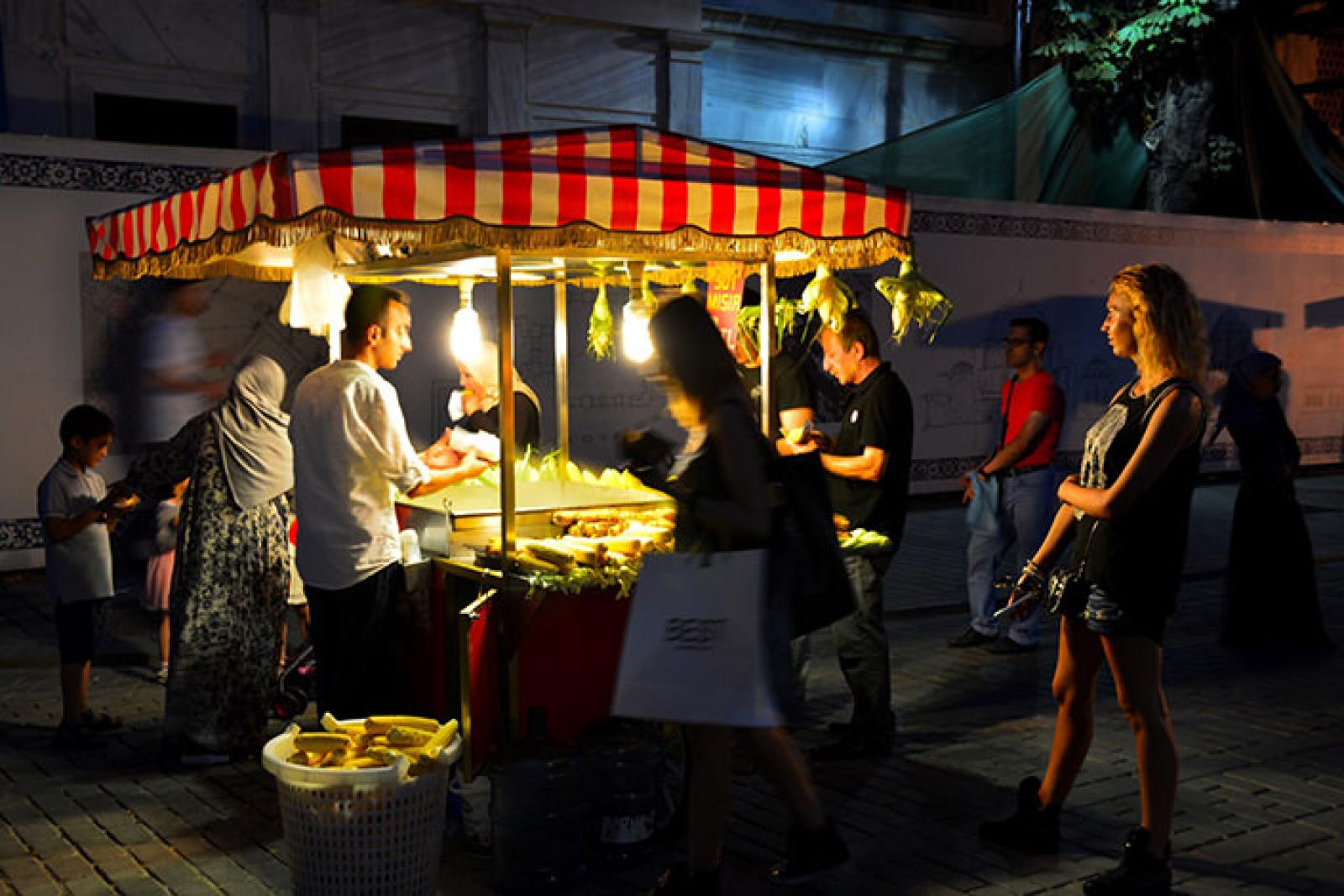 Customers gather at a brightly lit Lebanese street food stall at night
