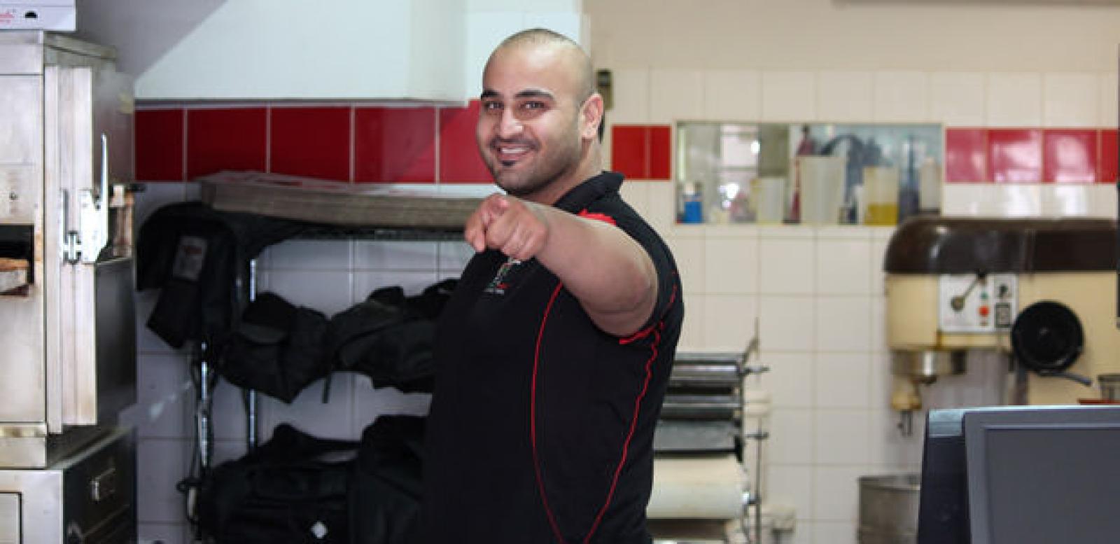 Smiling OOSHMAN team member preparing food in a commercial kitchen