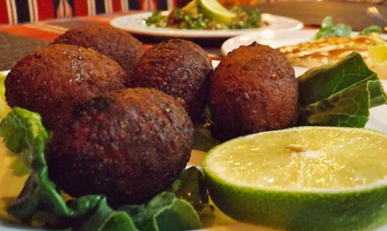 Crisp falafel balls served with fresh lime wedges and leafy herbs