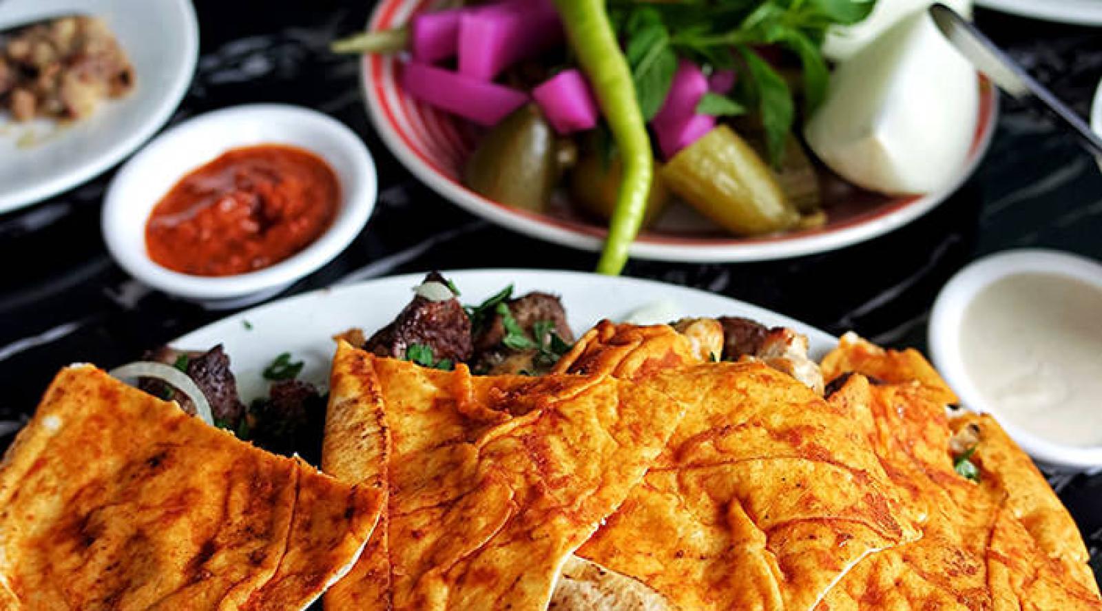 Golden Lebanese meat flatbreads served with pickles, chilli sauce and fresh herbs